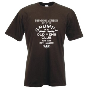 Peut inclure: T-shirt marron avec un texte blanc qui dit "Membre fondateur du club des vieux grincheux. Jamais heureux sauf en se plaignant."