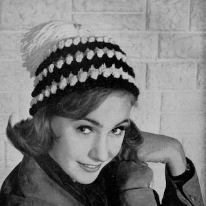 May include: A black and white crocheted hat with a white pom-pom on top. The hat has a wide brim and is made with a chunky yarn.