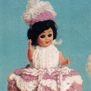 May include: A crocheted doll dress with pink and white stripes and a white crocheted hat. The dress is designed to fit a small doll and has a ruffled skirt.