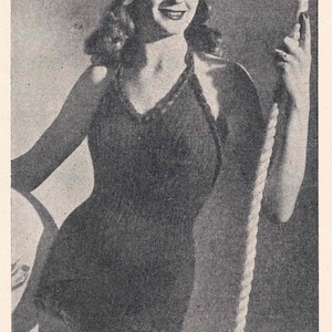 Peut inclure: Un maillot de bain noir avec un décolleté halter et un détail en corde. Le maillot de bain est porté par une femme aux cheveux ondulés et un sourire.