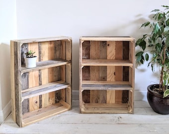 May include: Two rustic wooden bookshelves, each with three shelves, made from reclaimed wood in shades of brown and grey. One shelf holds a small potted plant. The shelves are freestanding and suitable for a variety of uses.