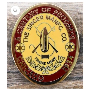 Könnte beinhalten: Eine ovale Gedenkmedaille aus Metall mit cremefarbenem Zentrum und dunkelrotem Rand. Der Text lautet A CENTURY OF PROGRESS, THE SINGER MANFC. CO., TRADE MARK, CHICAGO und 1934. Sie zeigt ein Nähschiffchen und Nähnadeln als Motiv.