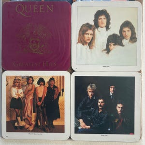 May include: A collection of four square Queen-themed coasters. One coaster shows the "Greatest Hits" album cover. The other three feature band photographs, including one captioned "Queen, 1974."