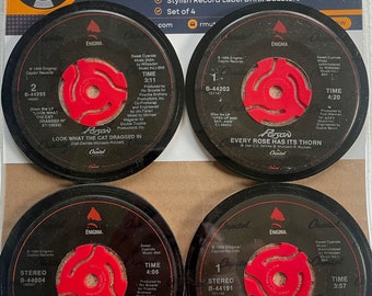 Puede incluir: Conjunto de cuatro posavasos de vinilo negro con etiquetas centrales rojas. Cada posavasos presenta una portada de álbum diferente de la banda Poison. Los títulos de los álbumes son "Look What The Cat Dragged In", "Every Rose Has Its Thorn", "Poison Play Dirty" y "Fallen Angel".