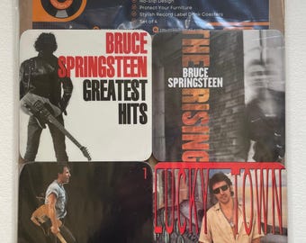 May include: Set of four square vinyl coasters featuring images of Bruce Springsteen. The coasters feature album covers from "Greatest Hits", "The Rising", and "Lucky Town".