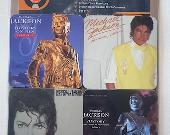 May include: Set of four vinyl coasters featuring album covers from Michael Jackson's music. The coasters feature images of Michael Jackson from different albums, including "History on Film, Volume II", "Man in the Mirror", "Human Nature", and "History: Past, Present and Future, Book I".