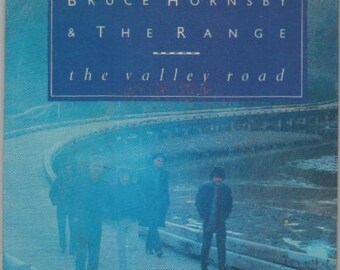 May include: A blue and white promotional coaster featuring the text "Bruce Hornsby & The Range" and "the valley road". The coaster features a blurry image of a band performing on a stage.