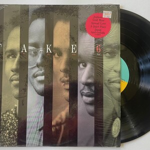 May include: Vinyl record album cover with a black and white photo of six men. The album title is "TAKE 6" and features the song titles "Gold Mine", "Spread Love", "A Quiet Place", "Don't", and "Goliath".