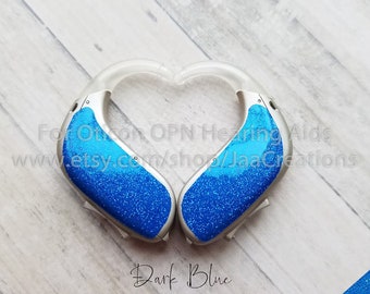 May include: Two blue glitter hearing aid covers in the shape of a heart. The text "Dark Blue" is written below the covers. The text "decal is not ombre" is written below the blue glitter sample.