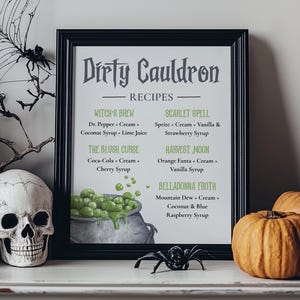 May include: A framed print with the text "Dirty Cauldron Recipes" and a cauldron illustration. The print is surrounded by Halloween decorations, including pumpkins, skulls, and a spider.