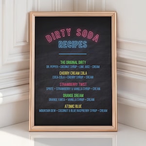 May include: A framed chalkboard sign with the words "DIRTY SODA RECIPES" in neon-style lettering. The sign lists recipes for various soda concoctions, including "The Original Dirty" and "Atomic Blue". The frame is gold.