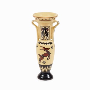 May include: A beige ceramic vase with black and red geometric designs and a stylized animal figure. The vase has two handles and a wide mouth.