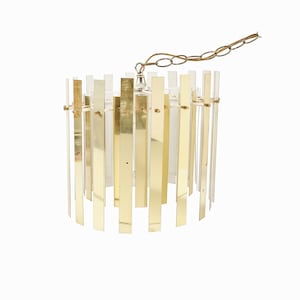 May include: A gold and clear glass pendant light fixture with a chain hanging from the top. The fixture is made of vertical strips of glass and metal.