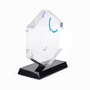 May include: A clear acrylic award with a hexagonal base and a blue design. The award has a small hole in the center.