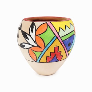 May include: A hand-painted ceramic pot with a cream-colored base and a vibrant, geometric design. The upper portion features a colorful array of shapes and patterns in red, orange, yellow, green, blue, and black. The rim is a reddish-brown color.