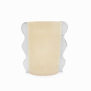 May include: A cream-colored glass vase with a wavy silver metal frame.