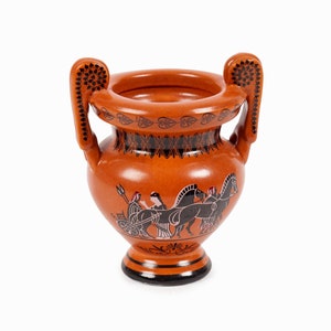 May include: A small, brown ceramic vase with two handles. The vase is decorated with a black and white design of a chariot pulled by horses.