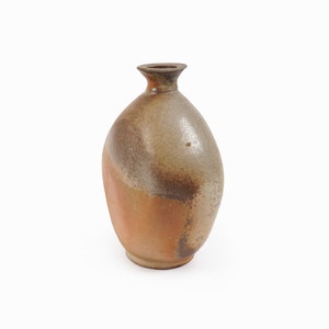 May include: A small, brown, ceramic vase with a rounded body and a narrow neck. The vase has a mottled glaze with shades of brown, gray, and white.
