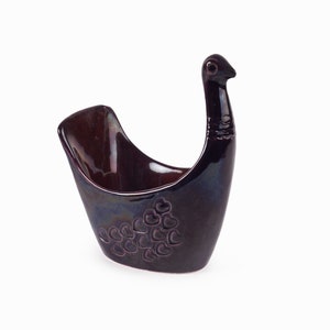 Puede incluir: Un plato de cerámica de color morado con forma de pájaro y un patrón de corazones. El plato está diseñado para contener objetos pequeños como joyas o llaves.