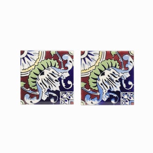 May include: Two square ceramic tiles with a colorful floral pattern. The tiles feature a blue, white, green, and red design with intricate details.