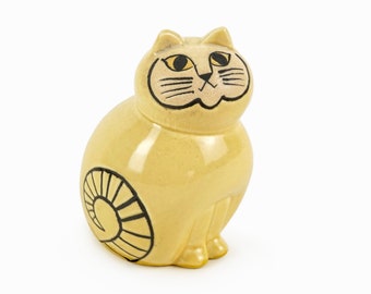 Może przedstawiać: Ceramiczna figurka kota w kolorze żółtym z czarno-białymi detalami. Kot siedzi z ogonem owiniętym wokół ciała.