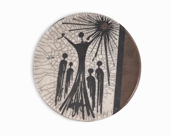 May include: A round ceramic plate with a crackled white glaze. The plate features a black and white illustration of a person with raised arms and five other people standing below. The illustration is surrounded by a black sunburst design.