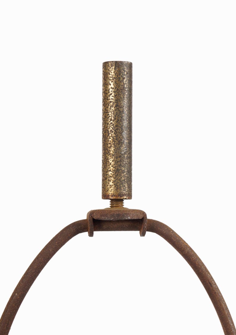 May include: Close-up of a vintage lamp component. The image shows a textured, cylindrical brass rod connected to a curved, rusty metal frame. The design features a threaded screw for attachment, suggesting a repair or restoration project.