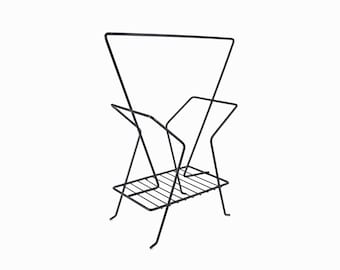 May include: Black metal magazine rack with a triangular frame and a wire shelf.