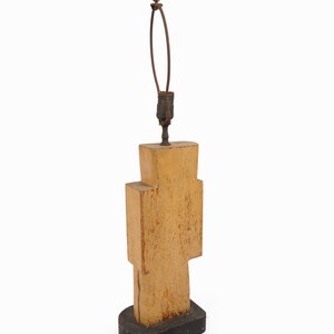 May include: A unique, geometric table lamp with a light brown, textured wooden body. The lamp has a black base and a brown cord. The lamp's height is approximately 20 inches.