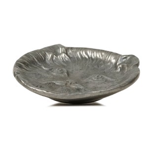 Puede incluir: Un plato de metal plateado con forma de cara de animal. El plato tiene una superficie texturizada y es perfecto para guardar objetos peque&ntilde;os.