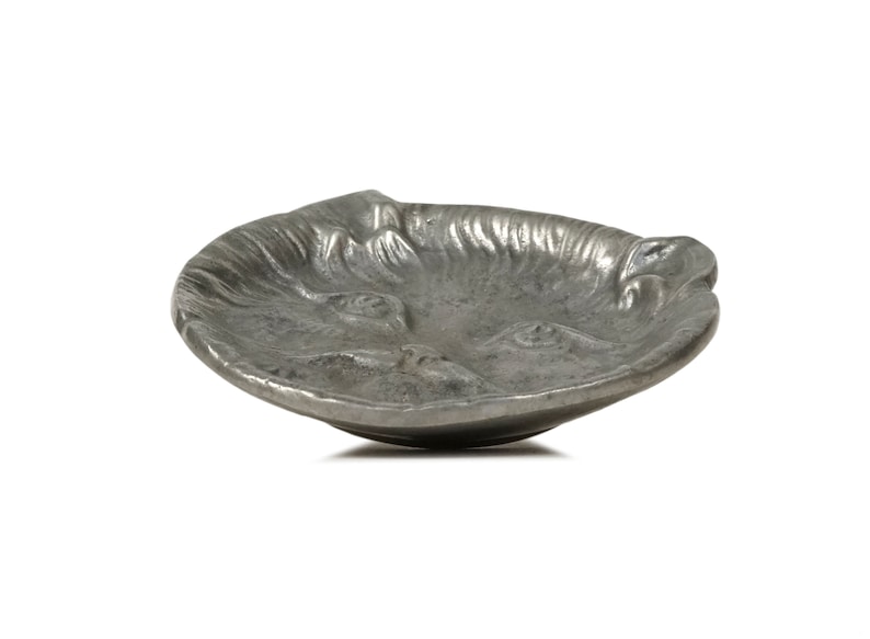 Puede incluir: Un plato de metal plateado con forma de cara de animal. El plato tiene una superficie texturizada y es perfecto para guardar objetos peque&ntilde;os.