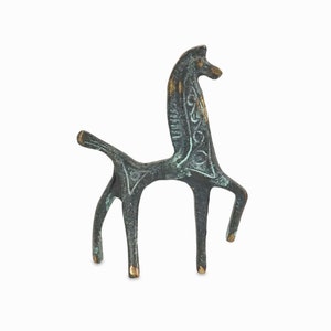 Puede incluir: Una escultura de bronce de un caballo estilizado con pátina verde y detalles dorados. El caballo está de pie sobre sus cuatro patas y tiene un cuello y una cola largos.