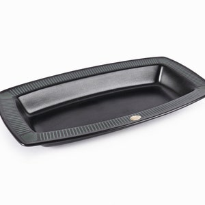 May include: A black rectangular serving dish with a green and black patterned border. The dish has a slightly raised centre.