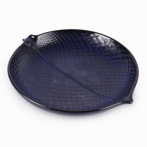 May include: A dark blue ceramic serving dish shaped like a leaf with a textured surface.