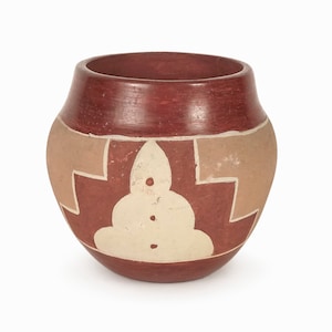 Puede incluir: Una pequeña olla redonda de barro rojo con un diseño geométrico en blanco y beige. La olla tiene un borde ligeramente acampanado y una base redondeada.