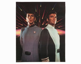 Puede incluir: Un póster vintage con dos hombres con uniformes de Star Trek, de pie sobre un fondo de espacio oscuro con rayas de luz. El texto "Star Trek" es visible en la parte inferior del póster.