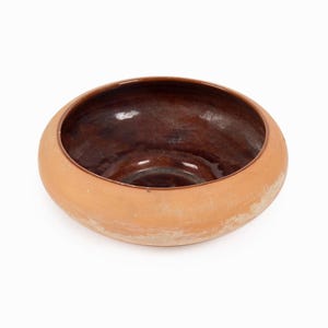 Könnte beinhalten: Eine handgefertigte, runde Keramikschale mit breitem, hellbraunem Rand und dunkelbraunem Innenraum. Die Schale hat eine glatte Außenseite und eine glänzende Innenseite. Das Design ist schlicht und rustikal, geeignet zum Servieren oder Ausstellen.