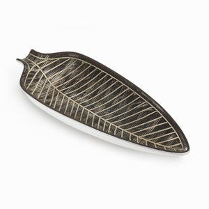 May include: A black and white ceramic leaf-shaped serving dish. The dish has a raised design of a leaf with veins.