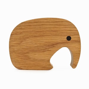Puede incluir: Una figurita de elefante de madera con un ojo negro, tallada en madera marrón claro.