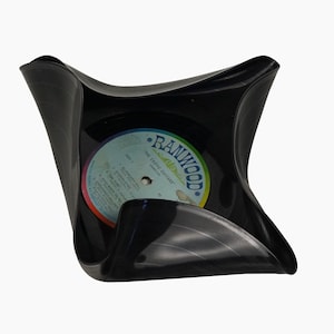 Peut inclure: Un disque vinyle noir a été transformé en un bol carré unique. L'étiquette du disque est visible, avec le texte "RANWOOD" et "THE EXOTIC GUITARS".