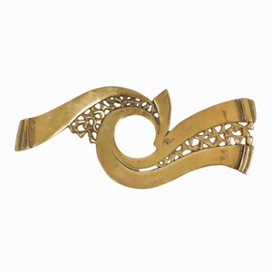 May include: A gold-colored metal decorative piece with a swirling design and a circular cutout in the center.