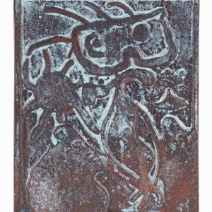 May include: A copper-colored ceramic tile with a raised design of a stylized figure. The figure is outlined in a lighter shade of copper and has a textured surface.