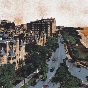 Puede incluir: Una vista a&eacute;rea de una calle de la ciudad bordeada de grandes edificios hist&oacute;ricos. La calle est&aacute; bordeada de &aacute;rboles y los coches conducen por la carretera. La calle termina en una playa con gente caminando por la orilla.