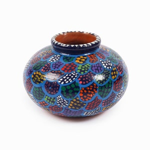 Peut inclure: Un vase en céramique peint à la main, de forme arrondie et à large ouverture. Le vase est décoré d'un motif d'écailles colorées dans les tons de bleu, vert, rouge, violet et blanc. Le bord est bleu foncé et l'intérieur est marron.