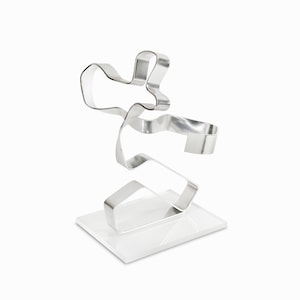 May include: A silver metal sculpture of a person in a dynamic pose, standing on a clear acrylic base.