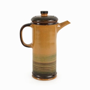 Könnte beinhalten: Eine braune Kaffeekanne aus Keramik mit einem dunkelbraunen Deckel und einem grün-braunen Streifenmuster.