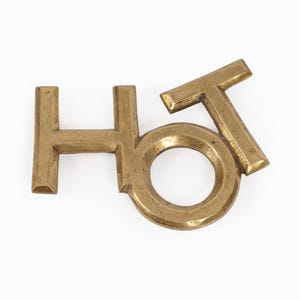 Puede incluir: Letrero de la palabra "hot" en letras de latón. Las letras están conectadas y la O es un anillo.