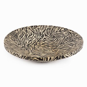 May include: A large, round wooden bowl with a black and white zebra print design.