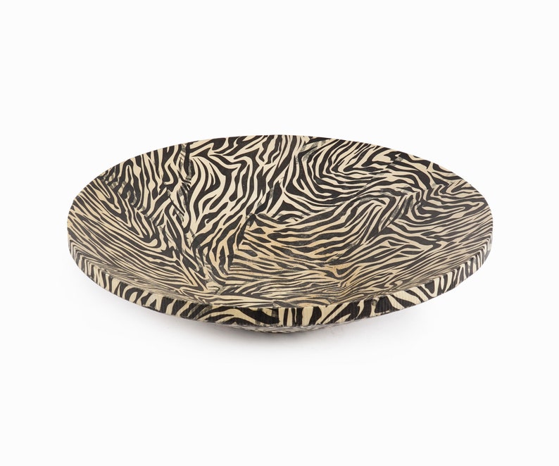 May include: A large, round wooden bowl with a black and white zebra print design.