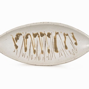May include: A white ceramic serving dish with a brown glaze design. The dish is oval shaped and has a slightly raised rim.